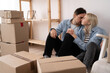 © mtrlin - Happy young couple sitting on the floor of the newly rented or purchased apartment. Unpacked cardboard boxes and covered furniture in the modern bright sweet home. moving and relocation