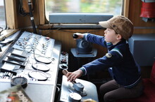 A Young Boy Steering A Locomotive And Train In A Driving Compartment Or Cabin With Handles And Meters As A Train Driver, Engine Driver, Engineman, Locomotive Driver, Engineer, Locomotive Handler