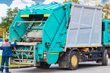 Fototapete - A garbage truck picks up garbage in a residential area. Loading mussar in containers into the car. Separate collection and disposal of garbage. Garbage collection vehicle.
