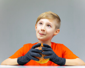 Wall Mural - the boy licks his lips while holding a sesame-sprinkled burger in front of him