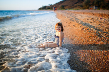 Wall Mural - European girl child alone on the seashore, wide angle shooting, vacation with children at sea