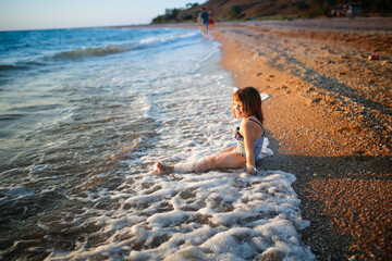 Wall Mural - European girl child alone on the seashore, wide angle shooting, vacation with children at sea