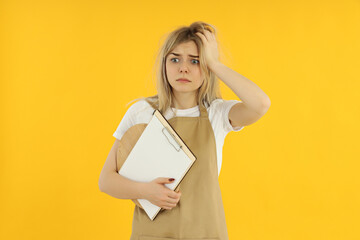 Wall Mural - Concept of occupation, young female waiter on yellow background