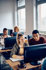 Young students cooperating while e-learning during computer class at university.