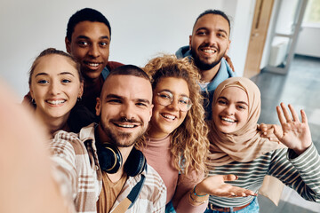 Multi ethnic group of happy college friends taking selfie in hallway.