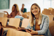 © Drazen - Happy female student using touchpad  at lecture hall and looking at camera.