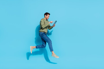 Poster - Full size portrait of sportive active person hold ereader write message jump isolated on blue color background