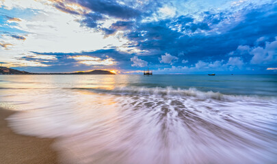 Wall Mural - Beautiful sunrise on the beach waves lapping at the shore of the soft great to welcome the new day