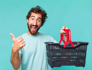 Wall Mural - young adult hispanic crazy man. empty shopping basket concept