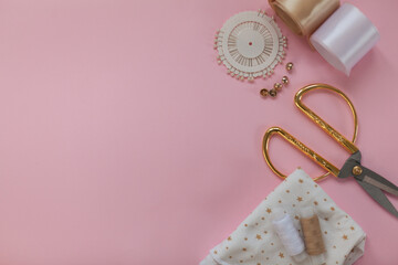 Wall Mural - The layout of sewing accessories and fabric on a pink background. Sewing threads, needles, fabric, buttons and scissors in gold and white. top view, flatlay with space for text