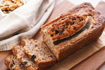 Wall Mural - Chocolate banana bread with walnuts on a wooden board and ingredients on a grey neutral background