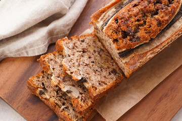 Wall Mural - Chocolate banana bread with walnuts on a wooden board and ingredients on a grey neutral background