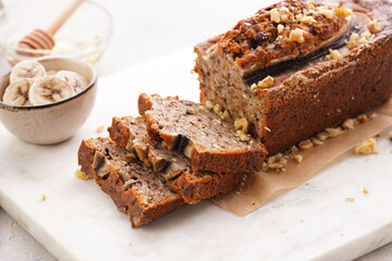 Wall Mural - Chocolate banana bread with walnuts on a marble board and ingredients on a grey neutral background