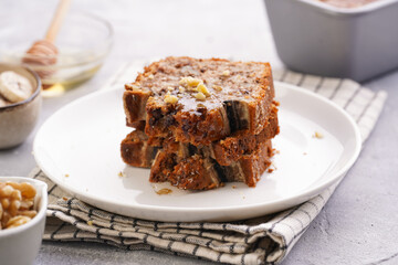 Wall Mural - Slices of Chocolate banana bread with walnuts on a checkered kitchen napkin and ingredients on a grey neutral background