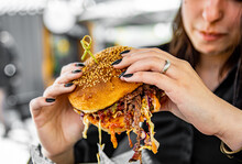 Woman Eating Street Food Burger Outdoors. Traditional Barbecue Pulled Beef Burger With Vegetables In Woman Hand