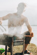 portrait of Smiling man seasoning meat on grill. Handsome man preparing barbecue, cooking beef meat at outdoor bbq party for friend. Close-up hand grilling sausages in nature at forest lake in summer