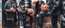 Scary Family, Mother, Father, Daughters Celebrating Halloween. Terrifying Black Skull Half-face Makeup And Witch Costumes, Stylish Images.Horror,fun At Children's Party In Barn On Street.Hats,jackets