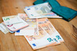 © Birute - Saving money. Keeping savings in wallet. Open purse with Euro banknotes out from it. Finance, savings, investing. Money management at home. Financial business concept