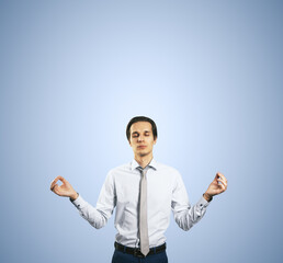 Poster - Calm down concept with man in white shirt in a zen pose isolated on light blue wall background with empty place for your text or logo, mock up