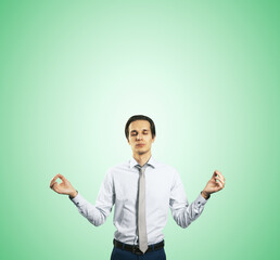 Poster - Calm down concept with man in white shirt in a zen pose isolated on light green wall background with empty place for your text or logo, mock up