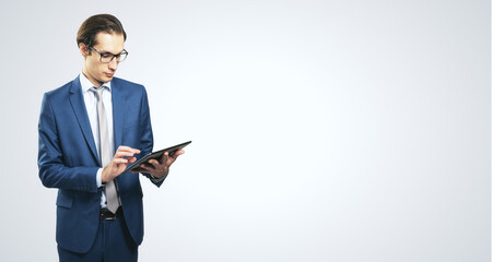 Poster - Young businessman in suit with digital tablet on white background with place for your text, mock up