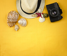 Yellow Bright Background With Seashells, Red Starfish, Camera, Straw Hat And Copy Space. Concept Of Freelancing, Leisure And Work On Vacation.