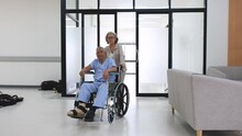 Elderly Woman Pushing A Wheelchair To An Old Man In The Hospital
