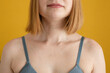 © ADDICTIVE STOCK - Anonymous young lady in bra standing against yellow background
