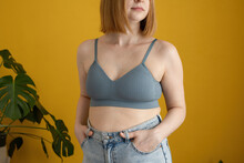 Anonymous Young Lady In Bra Standing Against Yellow Background