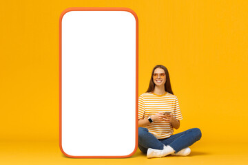 Smiling girl chatting with her boyfriend using smartphone, looking at huge copy screen template