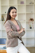 © ArLawKa - Successful Asian businesswoman smiling happily stands in front of office vertical desk.