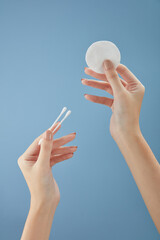 Wall Mural - Front view of hand model holding cotton pad in blue background for cosmetic advertising	