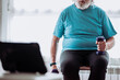 © ADDICTIVE STOCK - Anonymous elderly man watching video and exercising with dumbbells