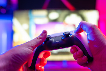 Wall Mural - Modern gamepad in the hands of a gamer. The concept is video games, hobby, recreation, communications, game strategy, gaming. Technological background. Neon lighting.