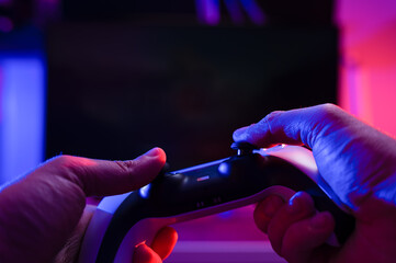 Canvas Print - A gamer holds a joystick in his hands on a black background. Concept - modern gadgets, electronics, digital technologies. Communication with friends online, virtual reality.