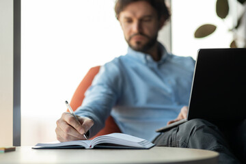 Aufkleber - Close up of man using laptop and writing in notebook