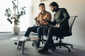 Poster - Serious male colleagues communicating at company office, using tablet pc, discussing common business project