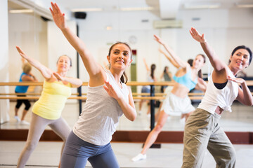 Wall Mural - Positive women practicing vigorous dance movements in group dance class