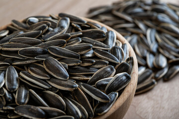 Black sunflower seeds in a bowl on wooden background	