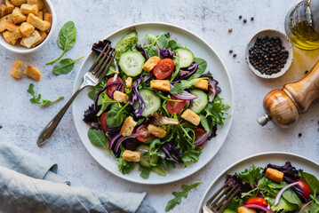 Top view of salads with lettuce, tomatoes and cucumbers on two plates.