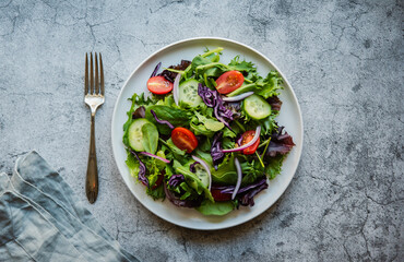 Top view of salad with lettuce, tomatoes and cucumbers on a plate.