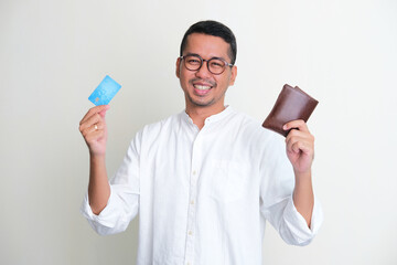 Adult Asian man smiling confident while showing his wallet and credit card