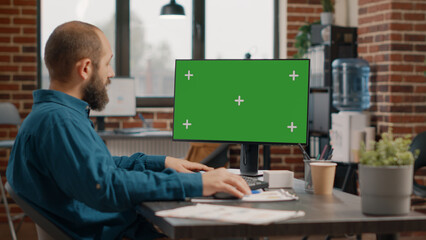 Wall Mural - Entrepreneur working with green screen on computer to plan business project. Employee using chroma key with isolated template and mockup background on monitor, designing strategy.