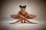 Beautiful nude sexy fitness girl with great figure flexing her perfect body in a yoga pose.