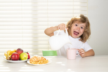 Wall Mural - Fuuny excited little boy pouring whole cows milk for breakfast. Schoolkid eating breakfast before school. Portrait of child sit at desk at home kitchen have delicious tasty nutritious breakfast.