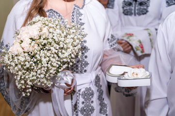 Wall Mural - wedding rings on the hands of the young, the creation of a new young family, in Ukrainian embroidered shirts