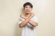 © herukru - Young Asian man wearing t-shirt putih cross arm disagree say no on isolate background