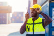 black worker African working engineer foreman radio control in port cargo shipping customs container yard