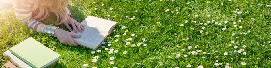 Young woman lying on the field and reading some books