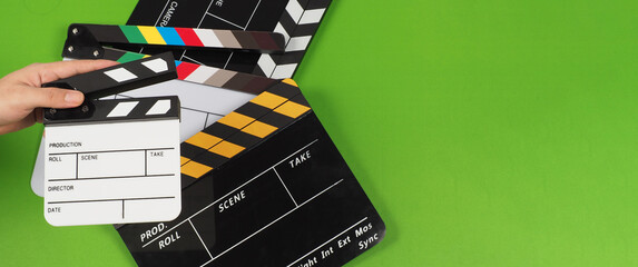 Hand hold small clapper board and 3 clapper boards oR movie slate on the green background floor.